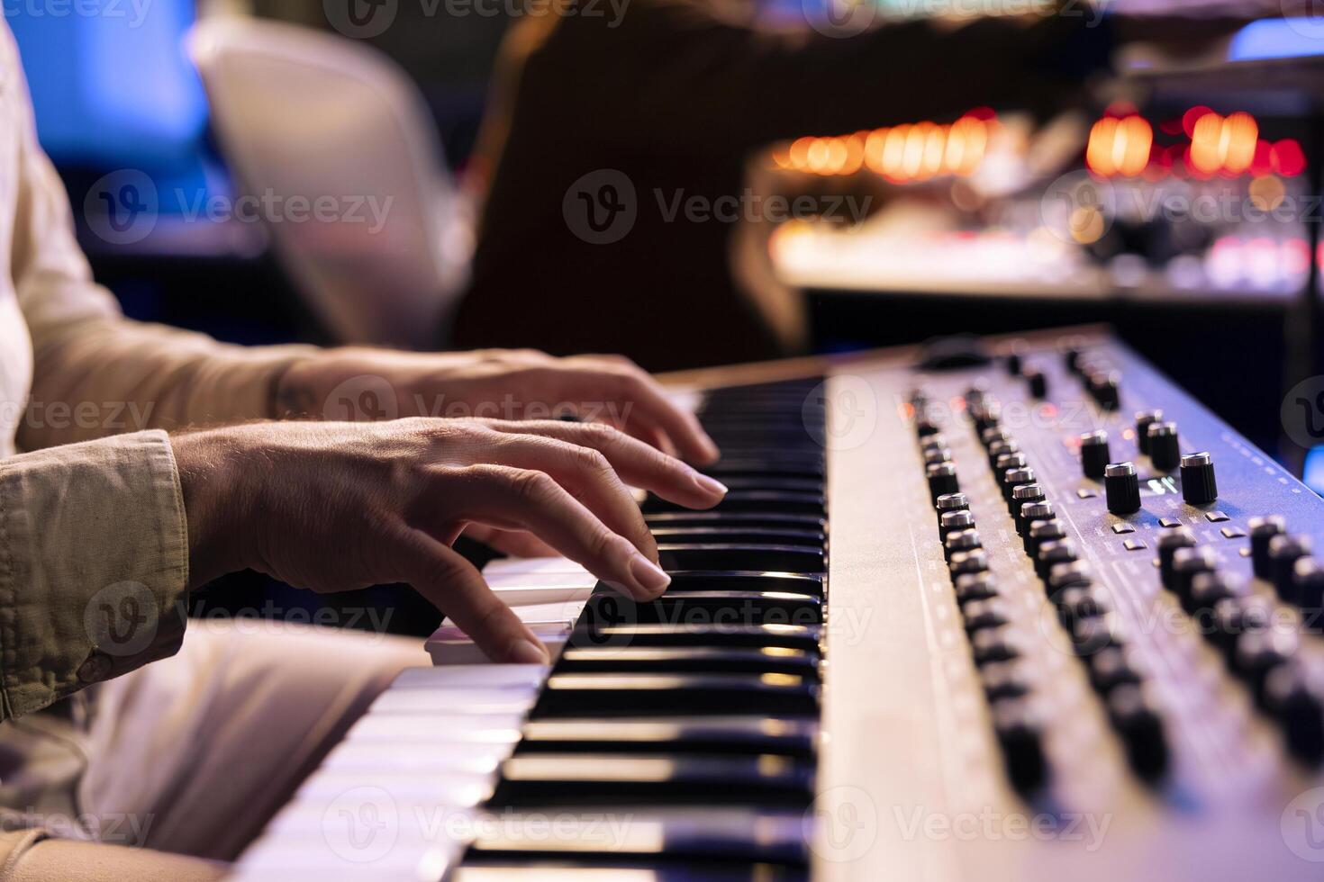 Male artist playing notes on electronic midi controller in studio, composing a new song with piano keyboard synthesizer. Skilled musician making a live performance in control room, music production. photo