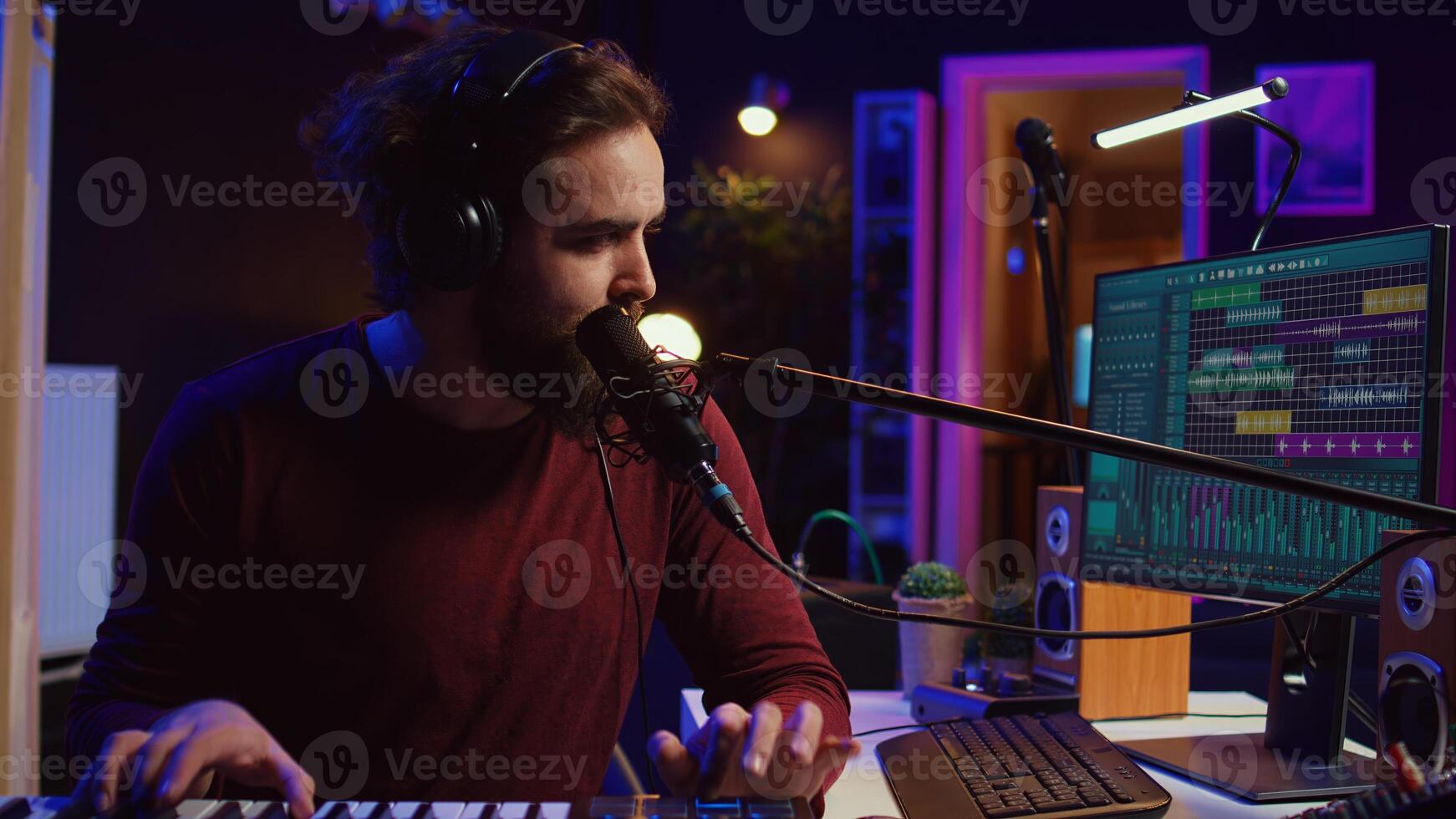 Songwriter recording a new song with microphone and midi controller, playing piano keys in home studio. Talented artist producing music with modern electronic keyboard and tools. Camera B. photo