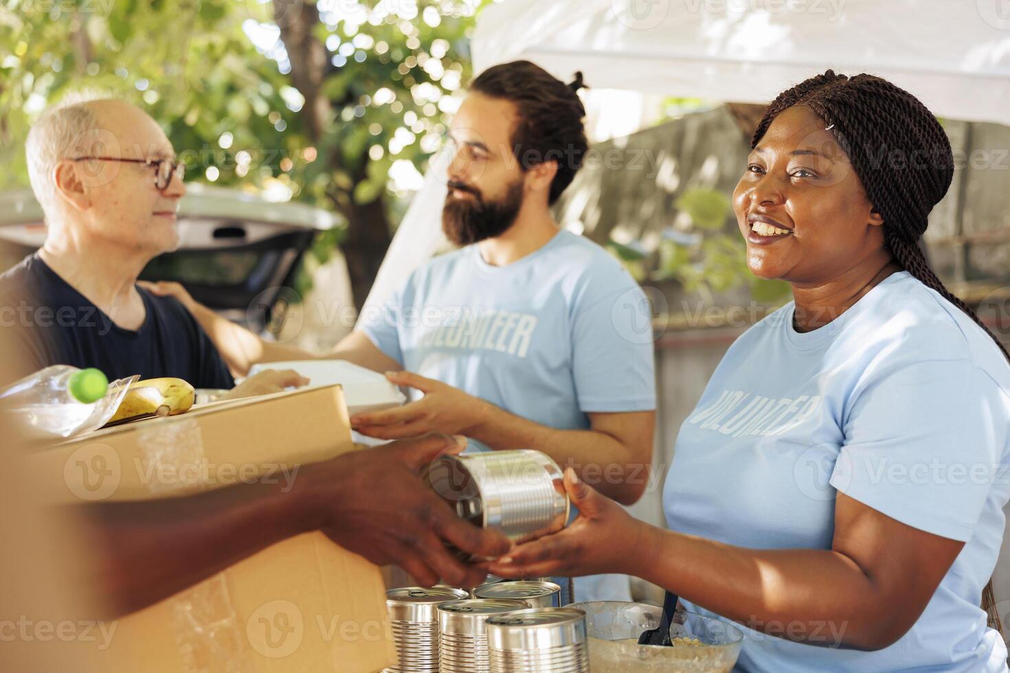 African american and caucasian volunteers provide aid, giving donation boxes filled with non-perishable items to the poor. Multiethnic team helps fight hunger and poverty through charitable efforts. photo