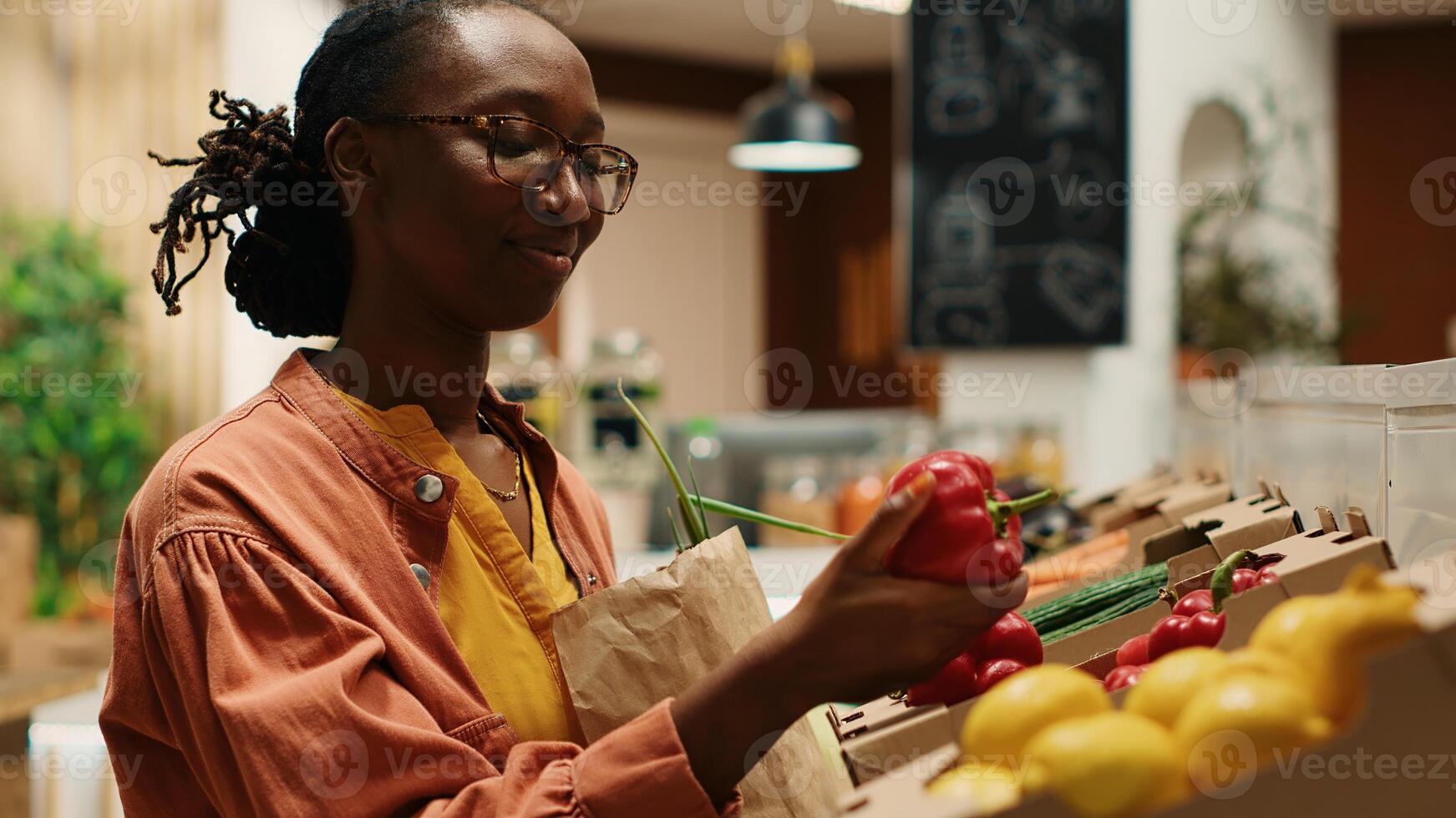 Vegan woman taking locally grown vegetables from crates, going grocery shopping at local farmers market. Regular customer choosing colorful ripe produce, nonpolluting farming business. Camera 1. photo