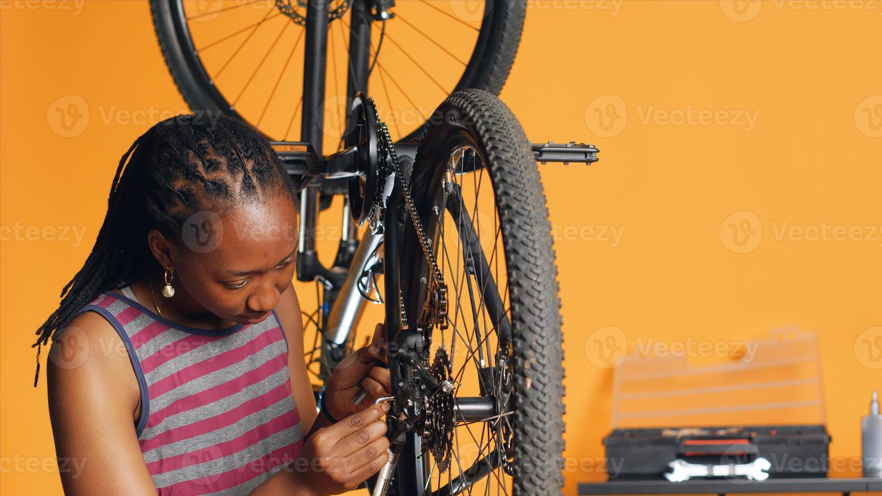 Specialist using screwdriver and hex socket wrench to secure wheel on bicycle in studio background repair shop. Technician screwing bolts on bike parts, fixing rear derailleur, camera A photo