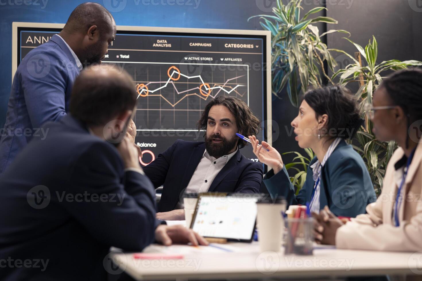 Teammates reviewing sales infographics on interactive board presentation, look into annual reports to understand what needs to change in order to expand the organization internationally. photo