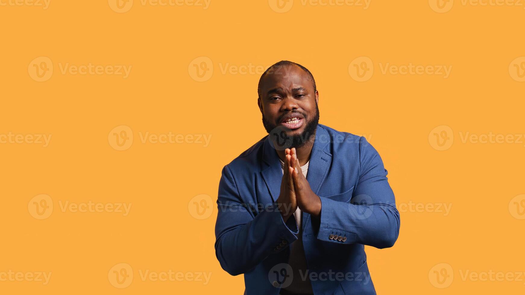 African american man putting hands together in begging gesture, making wish, isolated over yellow studio background. BIPOC person asking for something, praying and hoping, camera B photo