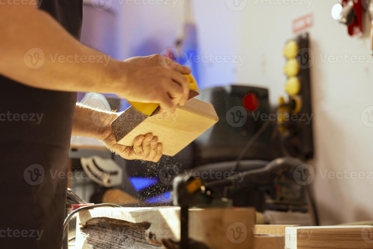 Man in studio using sandpaper for sanding wooden surface before painting it, ensuring adequate finish. Carpenter correcting damages suffered by wood using abrasive sponge photo