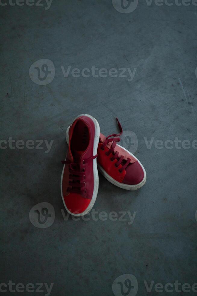 rojo brillante zapatillas en un gris hormigón piso foto