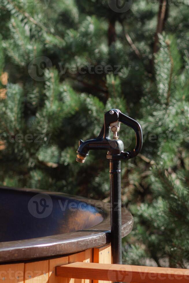 A massive black faucet is installed above the vat photo