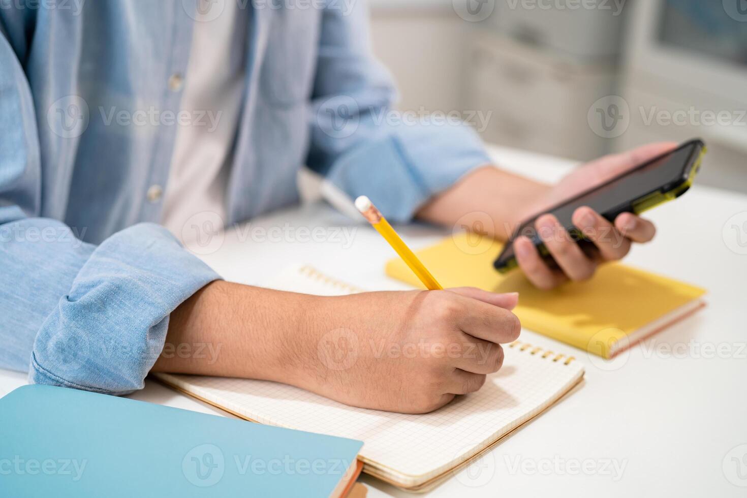 Adolescente escribir en cuaderno y utilizar móvil teléfono buscar datos en línea a en línea aprendizaje Universidad educación. foto