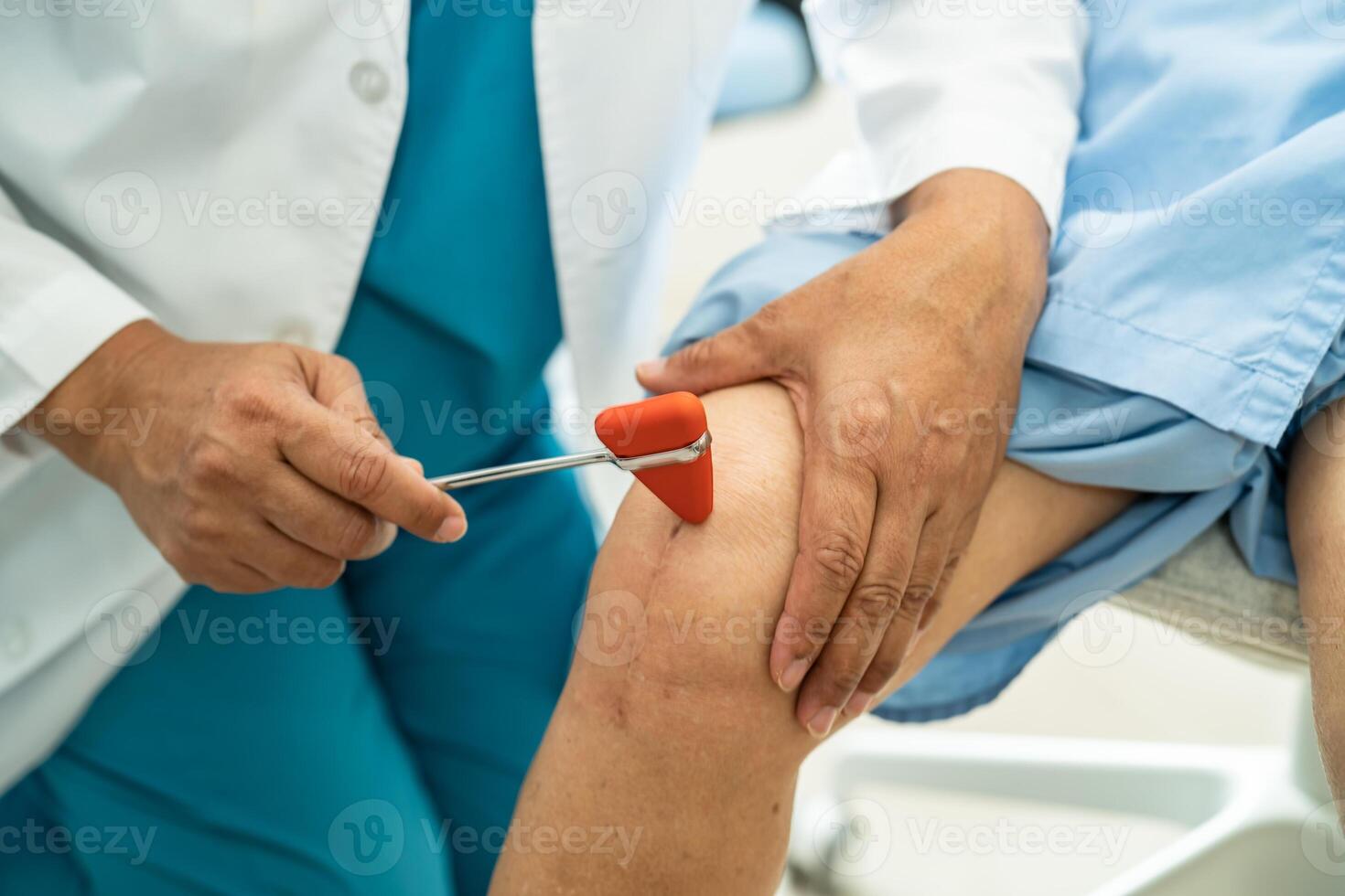 Asian doctor use hammer knock senior woman patient to check knee reflex, nerve and muscle in hospital. photo