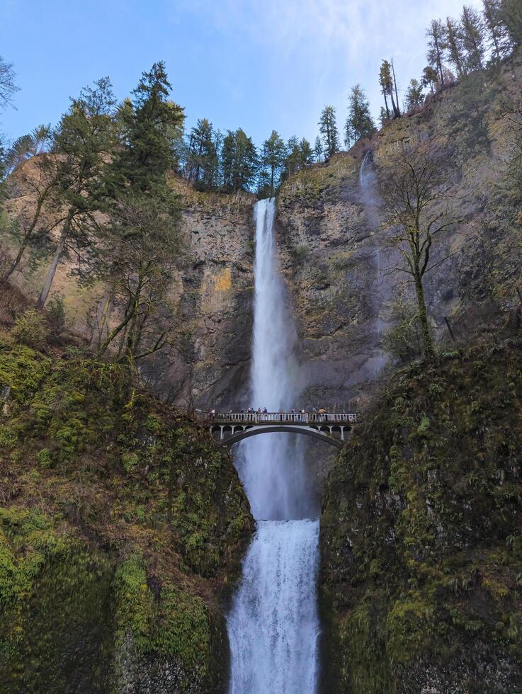 Columbia River Gorge, Oregon, USA - 02.24.2024 Tourists are enjoying a up-close view of roaring Multnomah Falls from Multnomah Creek Bridge. photo