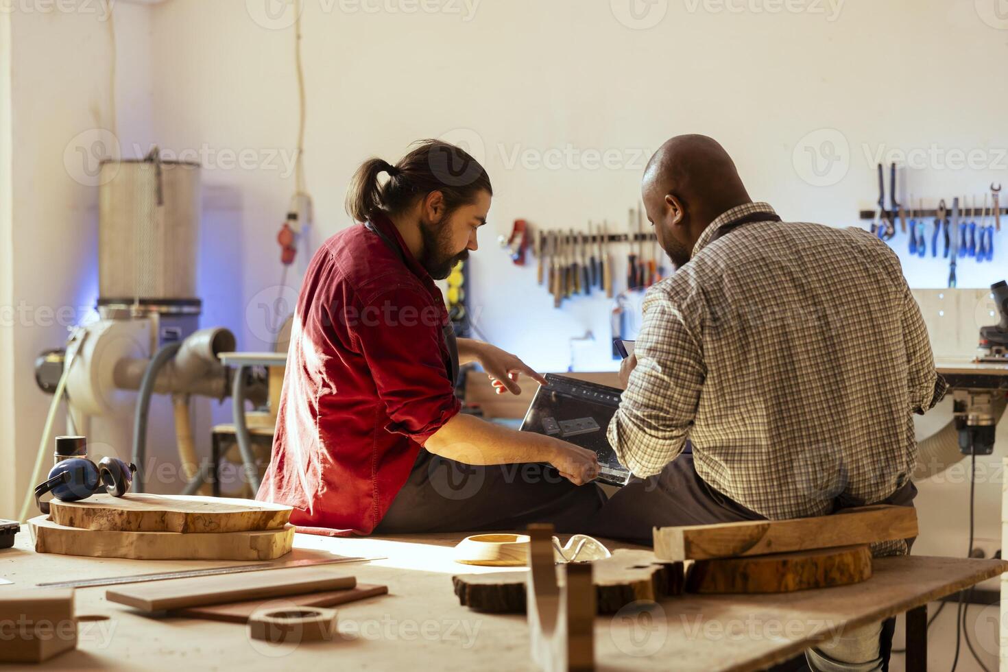 Carpenter looking over blueprints schematics on laptop in CAD software with apprentice. Woodworker and colleague designing custom 3D furniture on notebook in studio, preparing for client order photo