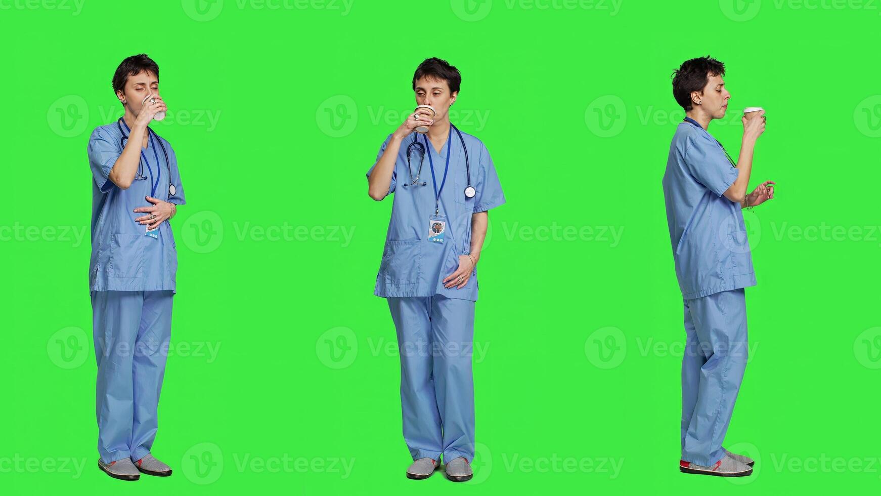 Healthcare specialist enjoying hot coffee cup against greenscreen backdrop, drinking caffeine refreshment in blue scrubs. Medical assistant serving beverage at work, friendly staff. Camera A. photo