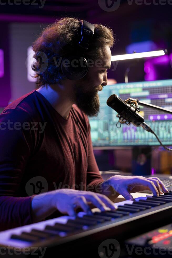 Sound engineer playing piano keyboard to compose new music, singing on microphone and adding audio effects in post production. Artist composer creating songs for music industry. photo