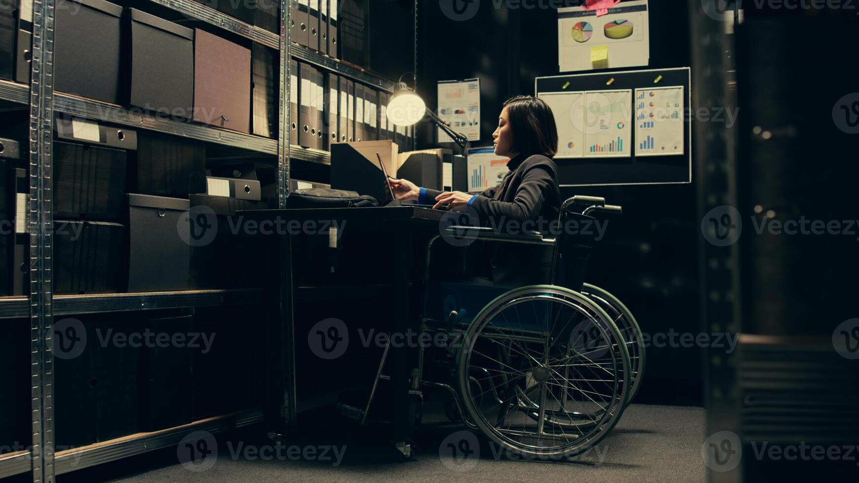 Wheelchair user conducting private investigation in disability friendly incident room, examining old cases to find connections. Detectives gathering legal information for identification. Camera B. photo