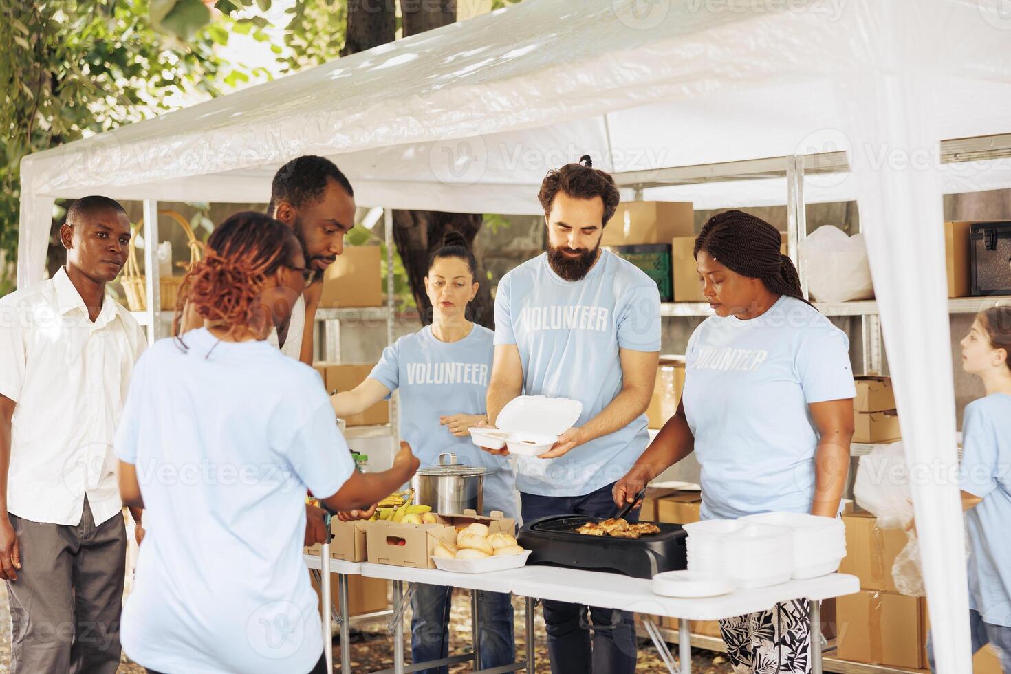 Empathetic service to the needy and poor multicultural team donates and provides humanitarian aid. African american man with crutches receives assistance from black volunteer woman at food drive. photo