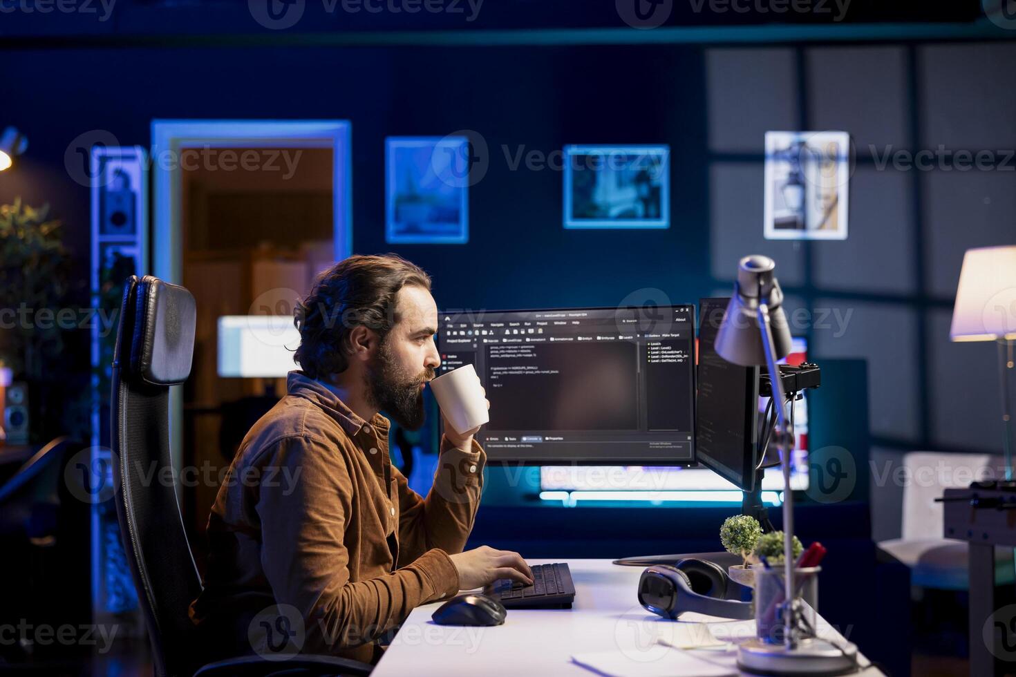 Man drinking coffee while doing software quality assurance, reading source code on computer. Developer inspecting coding on desktop PC and enjoying hot beverage, looking to fix potential issues photo