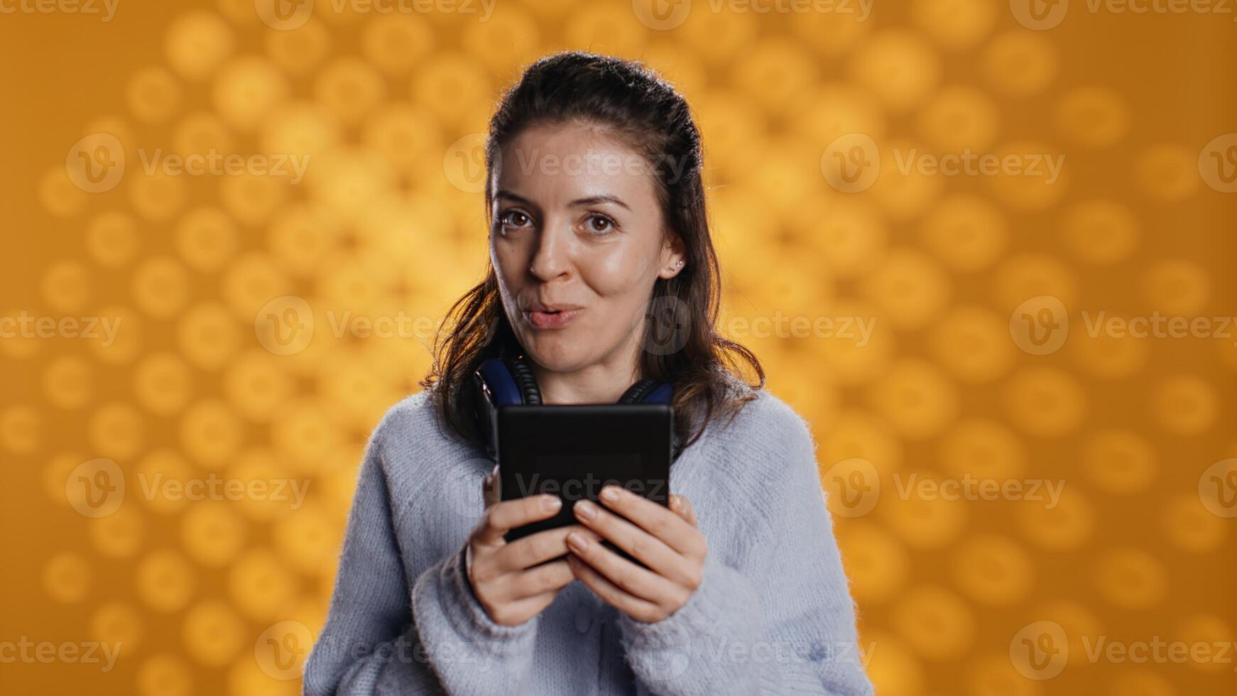 Voice actor reading ebook in entertaining manner in front of audience, portraying character, studio background. Woman reenacting digital novel for spectators, reading from tablet screen, camera B photo