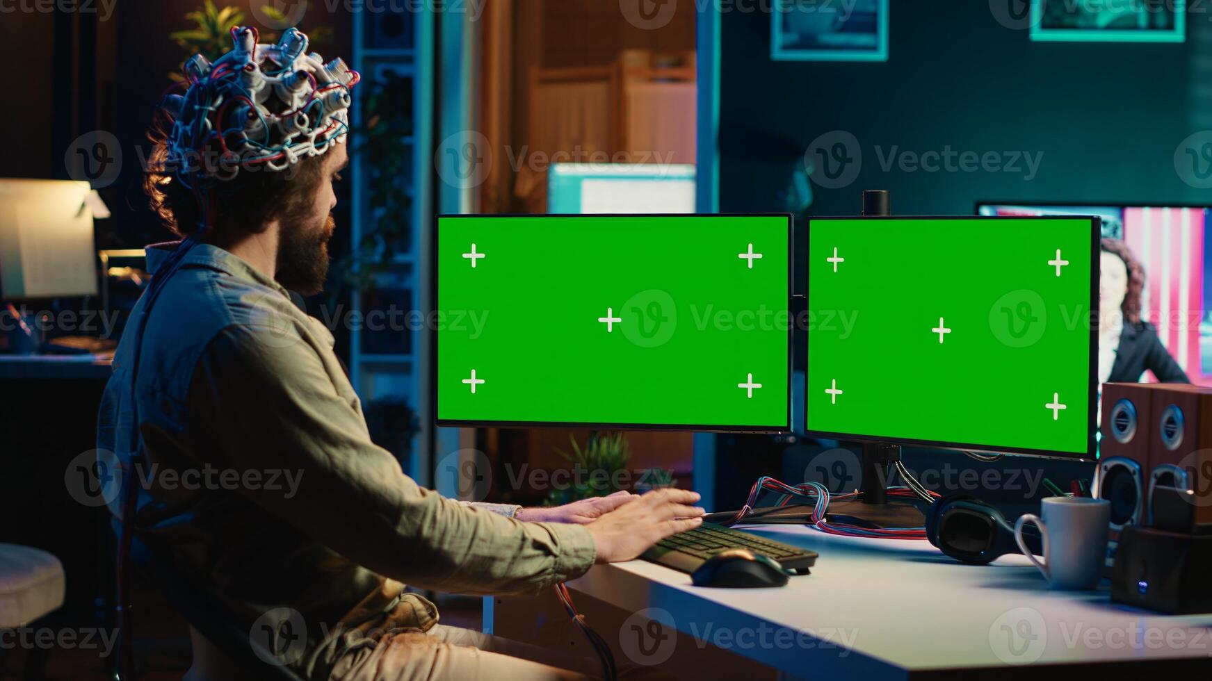 Computer engineer using EEG headset, starting mind upload process using green screen PC. Man using neuroscientific device to transfer consciousness into cyberspace with mockup monitors, camera A photo