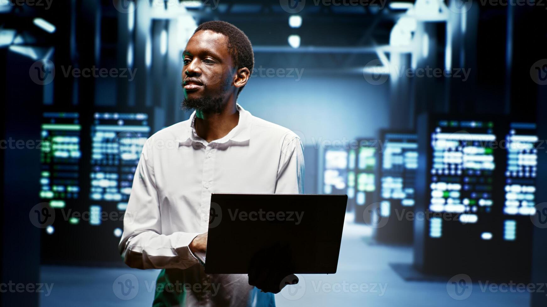 African american repairman using laptop to review energy consumption across server cabinets components. Manager making sure data center equipment temperature sensors are performing flawlessly photo
