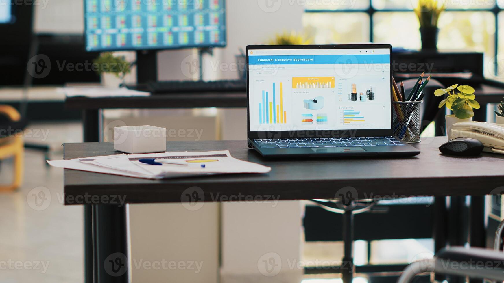 Wheelchair in office offering accessibility to workers with disability and laptop on desk showing business analytics with computer screen in background displaying stock exchange listings photo
