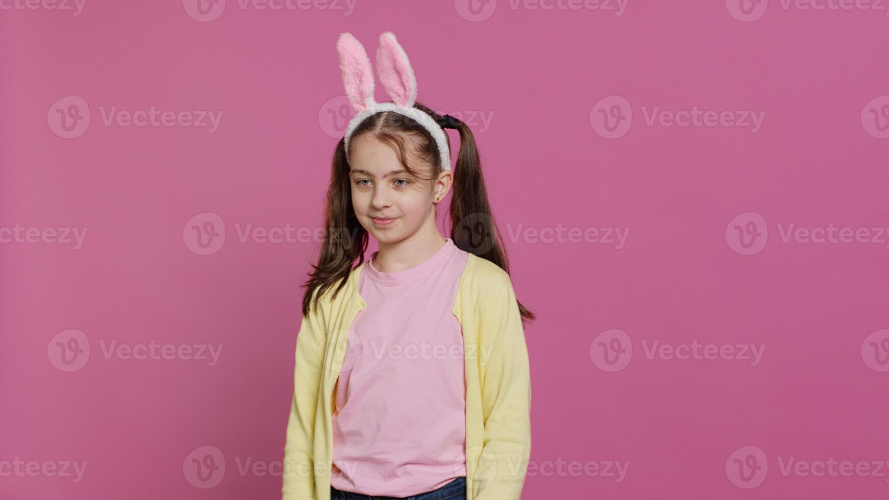 Confident cheery girl showing dance moves in the studio, feeling cheerful and positive about easter holiday festivity. Talented child dancing around and wearing bunny ears. Camera A. photo