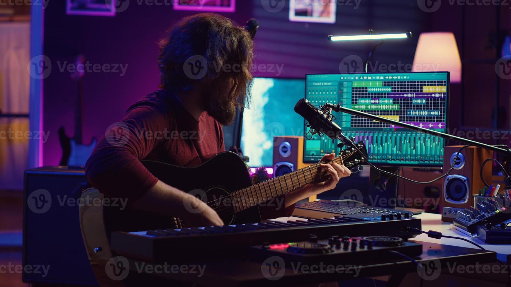 Creative songwriter singing a song on microphone and playing his guitar, acoustical engineering technology with daw software on pc. Artist creating music with instrument and mixing console. Camera A. photo