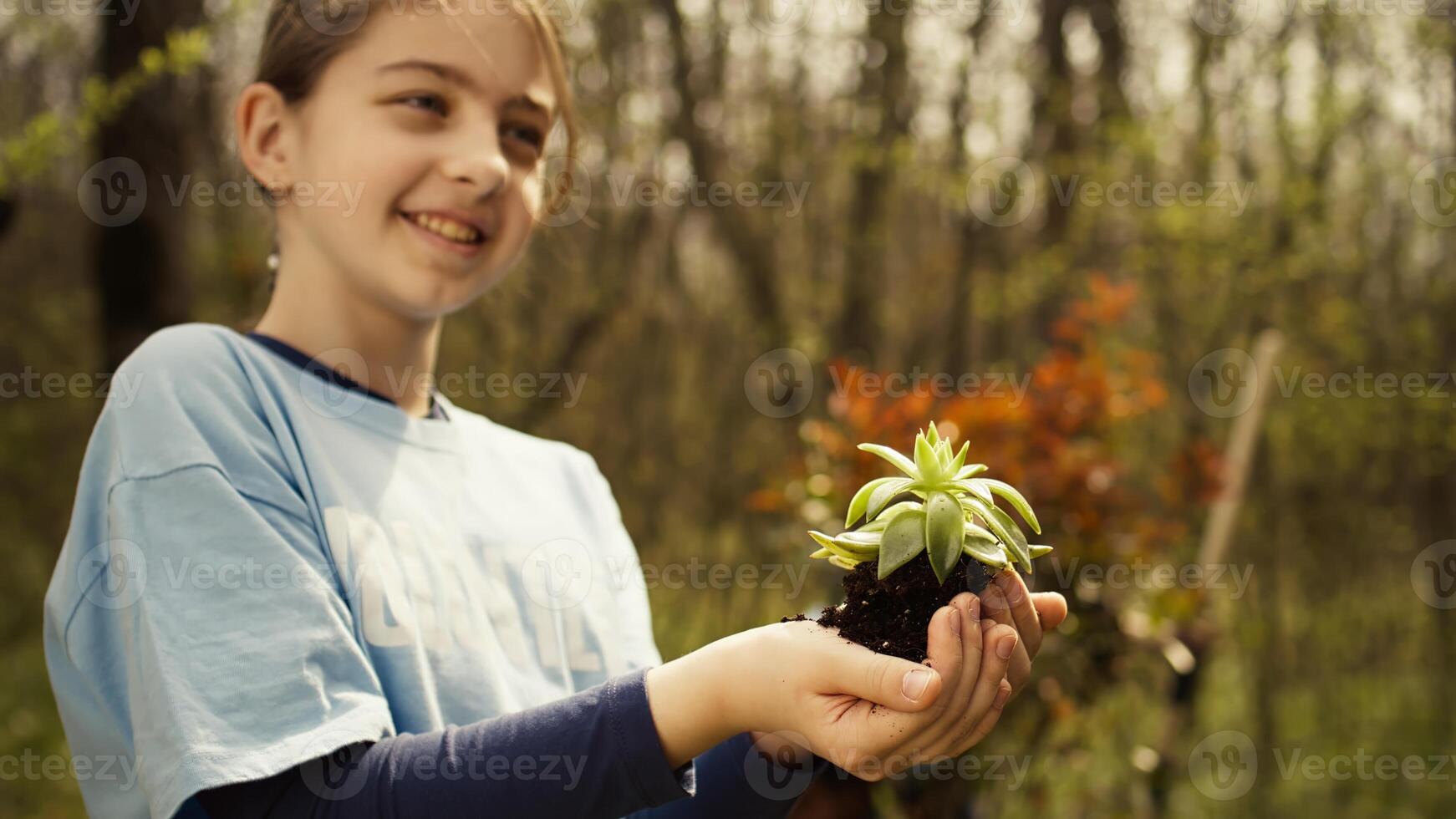 Cute child activist presenting a small seedling tree in her hands, fighting to protect the environment and natural ecosystem. Little girl working to conserve nature and plant trees. Camera B. photo