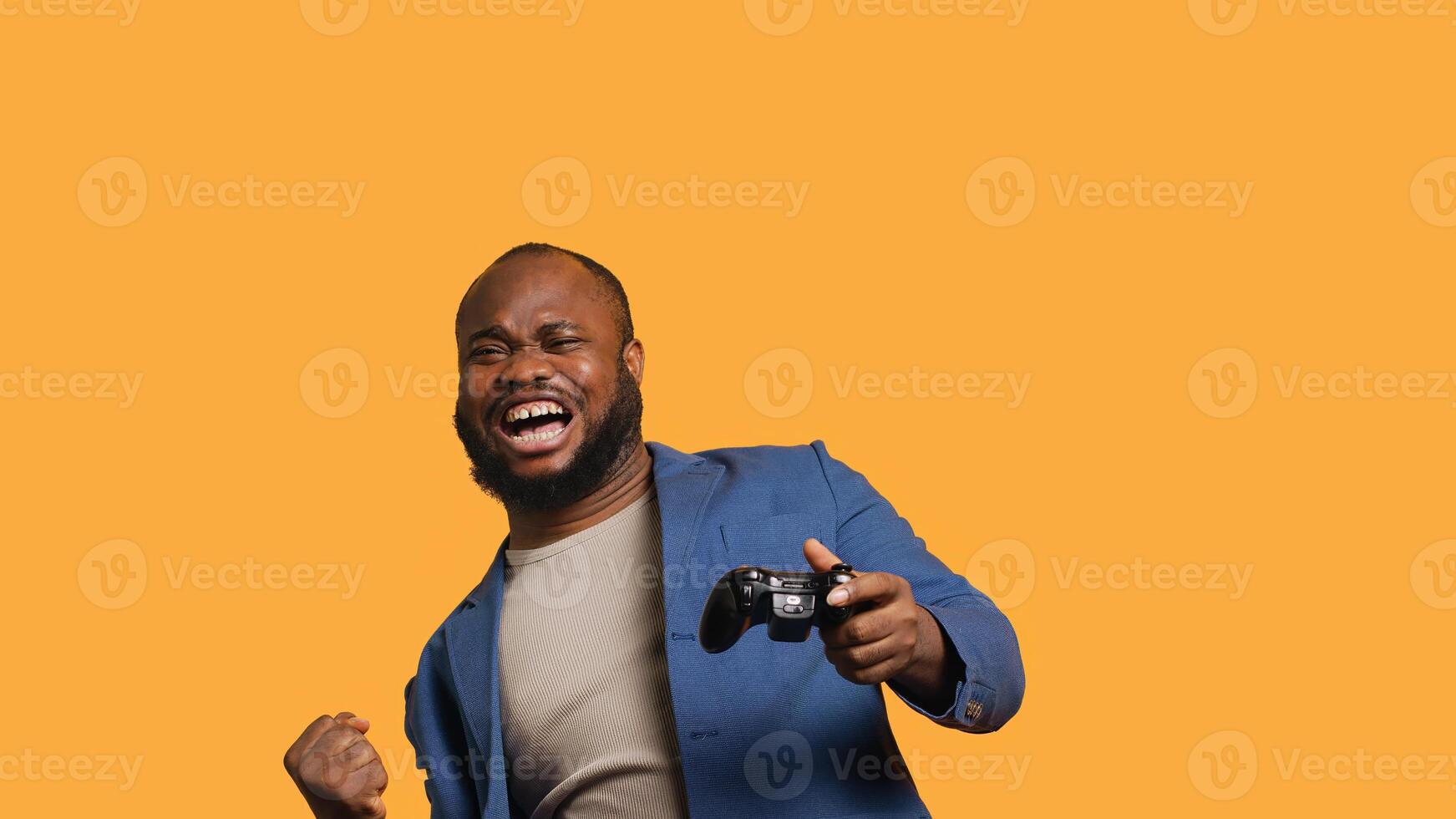 Joyous BIPOC gamer celebrating after winning gaming console game, studio background. Delighted man bragging after being victorious in videogame, defeating all enemies using gamepad, camera A photo