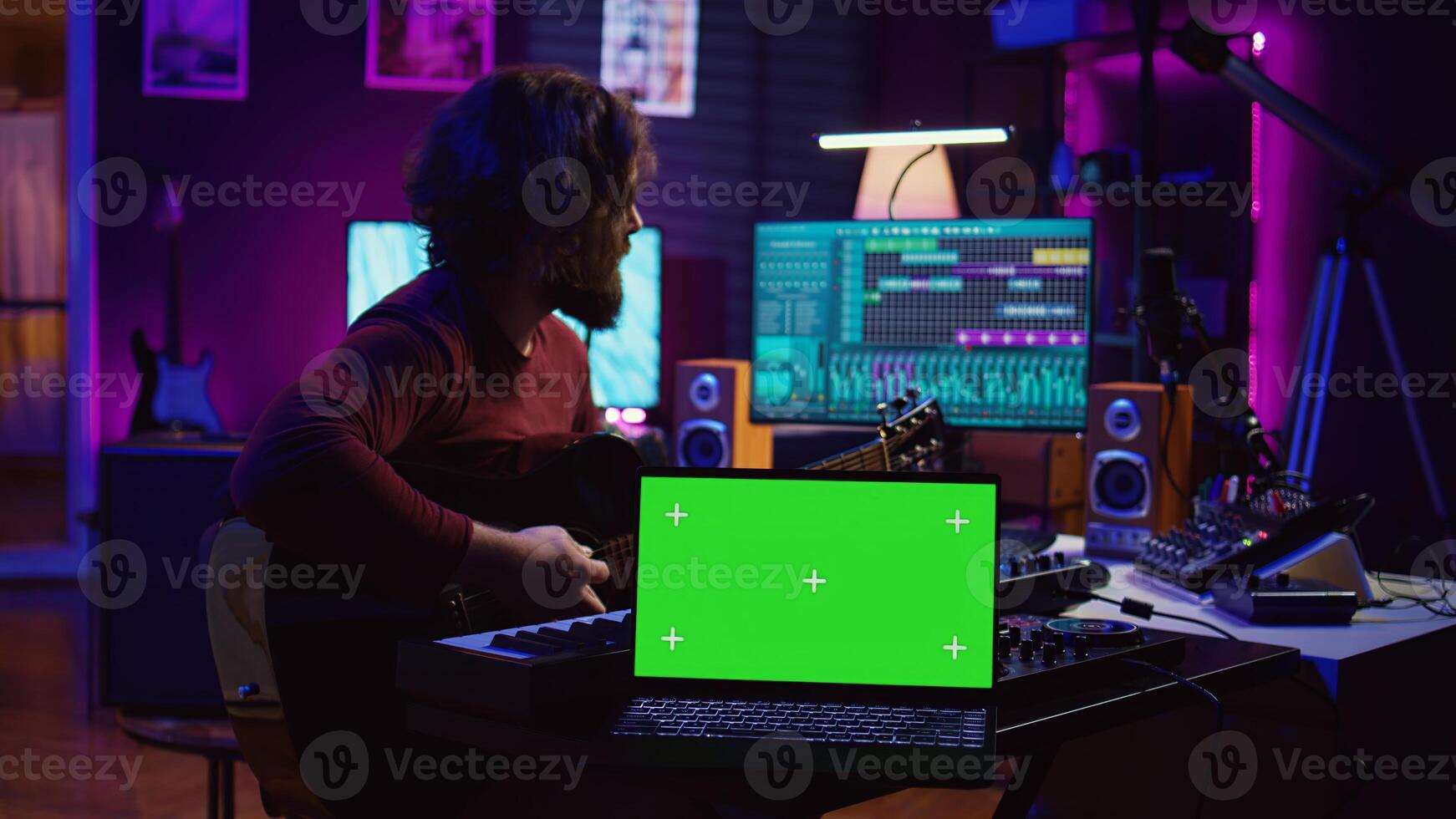 Guitarist playing his acoustic instrument next to greenscreen on laptop, learning new strings accords to play on guitar in home studio. Musician artist developing his singing skills. Camera B. photo