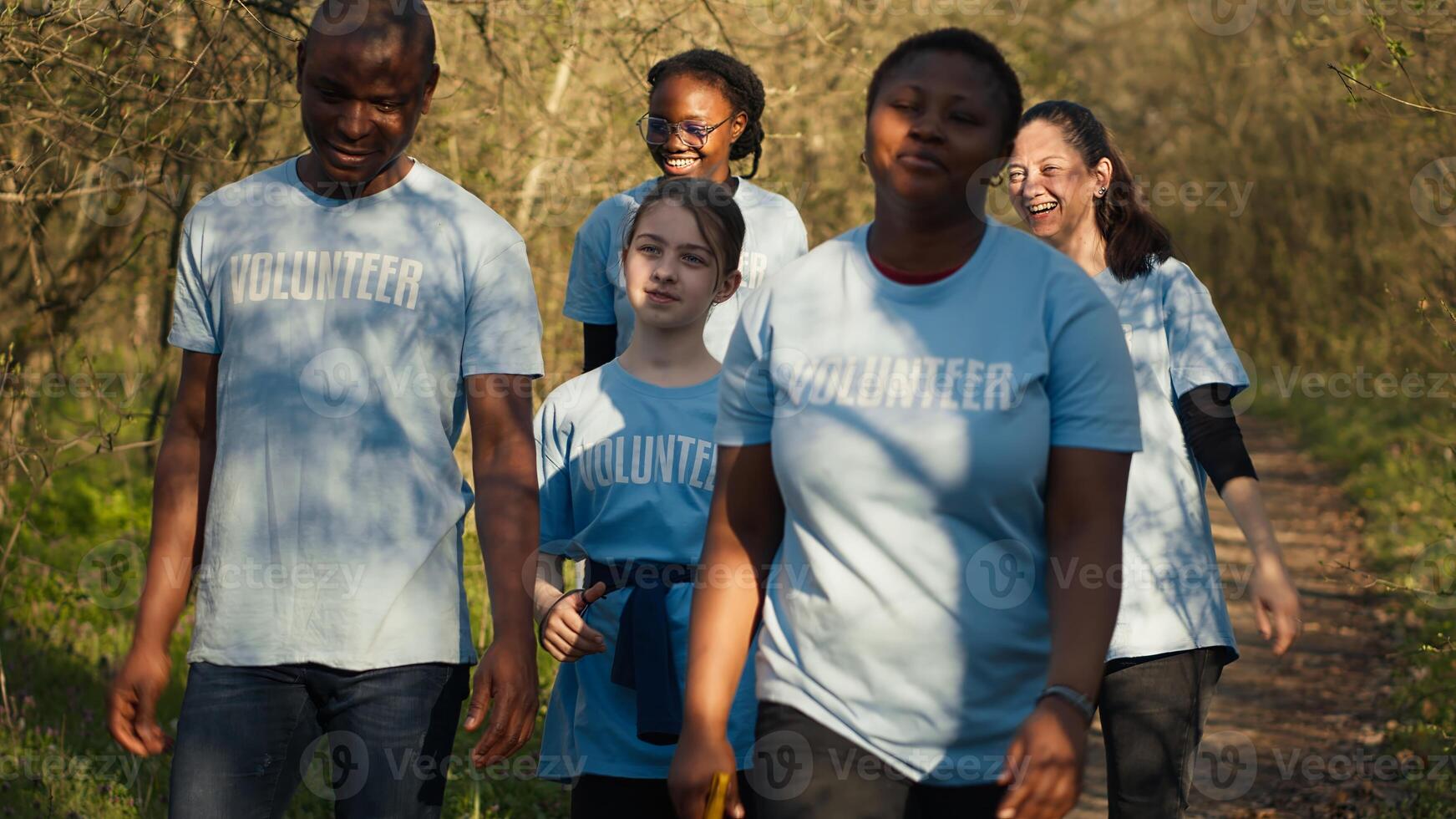 Satisfied people leaving the woods after a productive litter cleanup session, being successful in cleaning the forest environment from junk and plastic waste. Happy proud activists. Camera A. photo