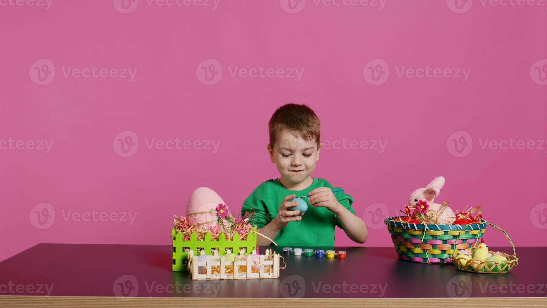 Little cheerful boy crafting handmade easter decorations by painting with watercolor and paintbrushes. Small young kid using art supplies coloring eggs for holiday, decorating activity. Camera B. photo