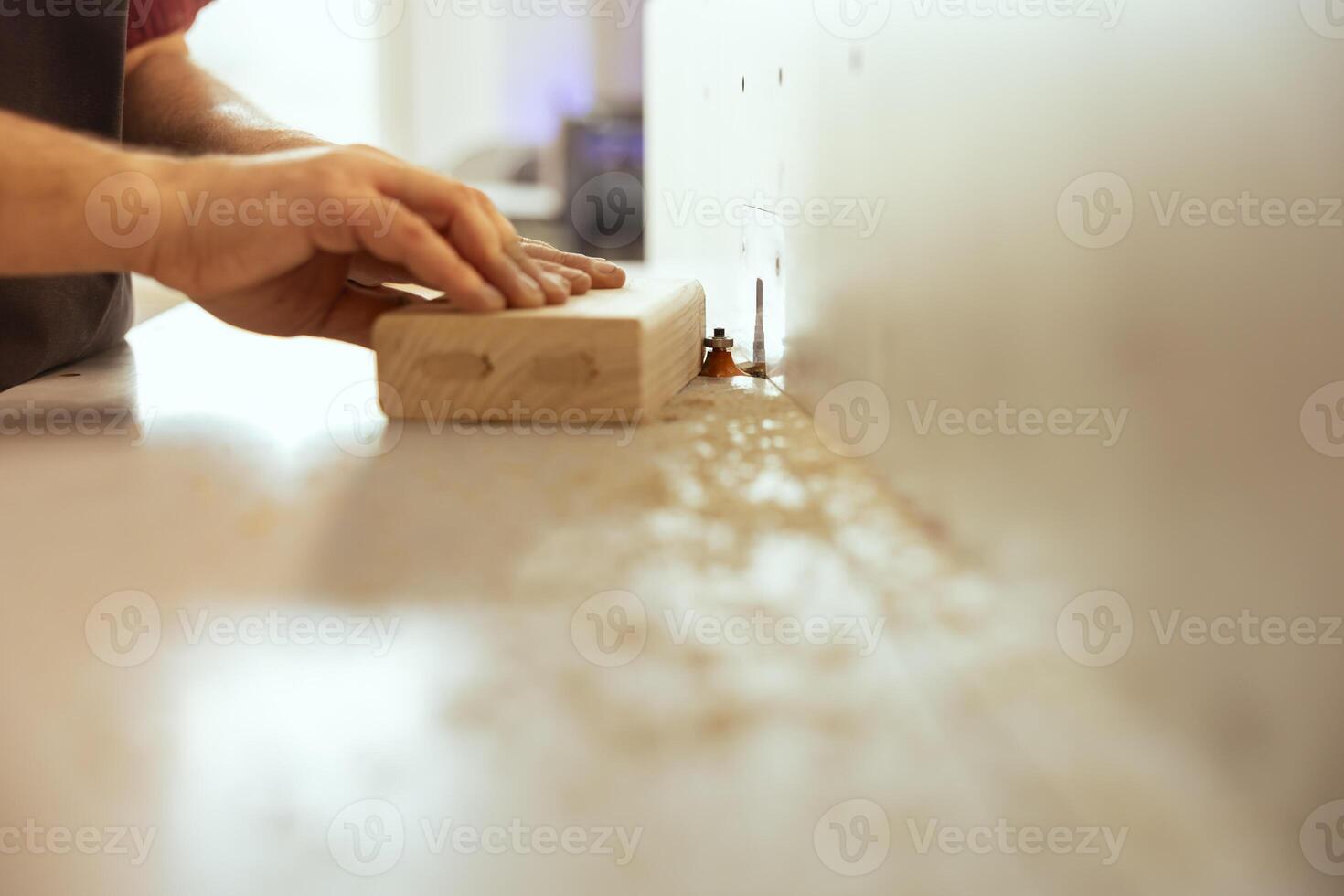 Cabinetmaker using wood shaper machinery to finish precise cutting on wood piece in studio. Woodworking professional in joinery shop using spindle moulder gear to do assembling photo