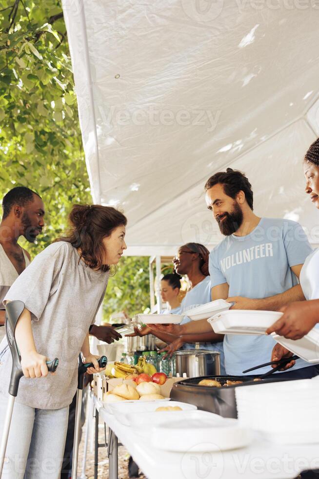 Multiethnic charity group gives back, providing free food, shelter, and support to the less fortunate. Smiling and happy volunteers helping the homeless, sick, and disadvantaged individuals in need. photo
