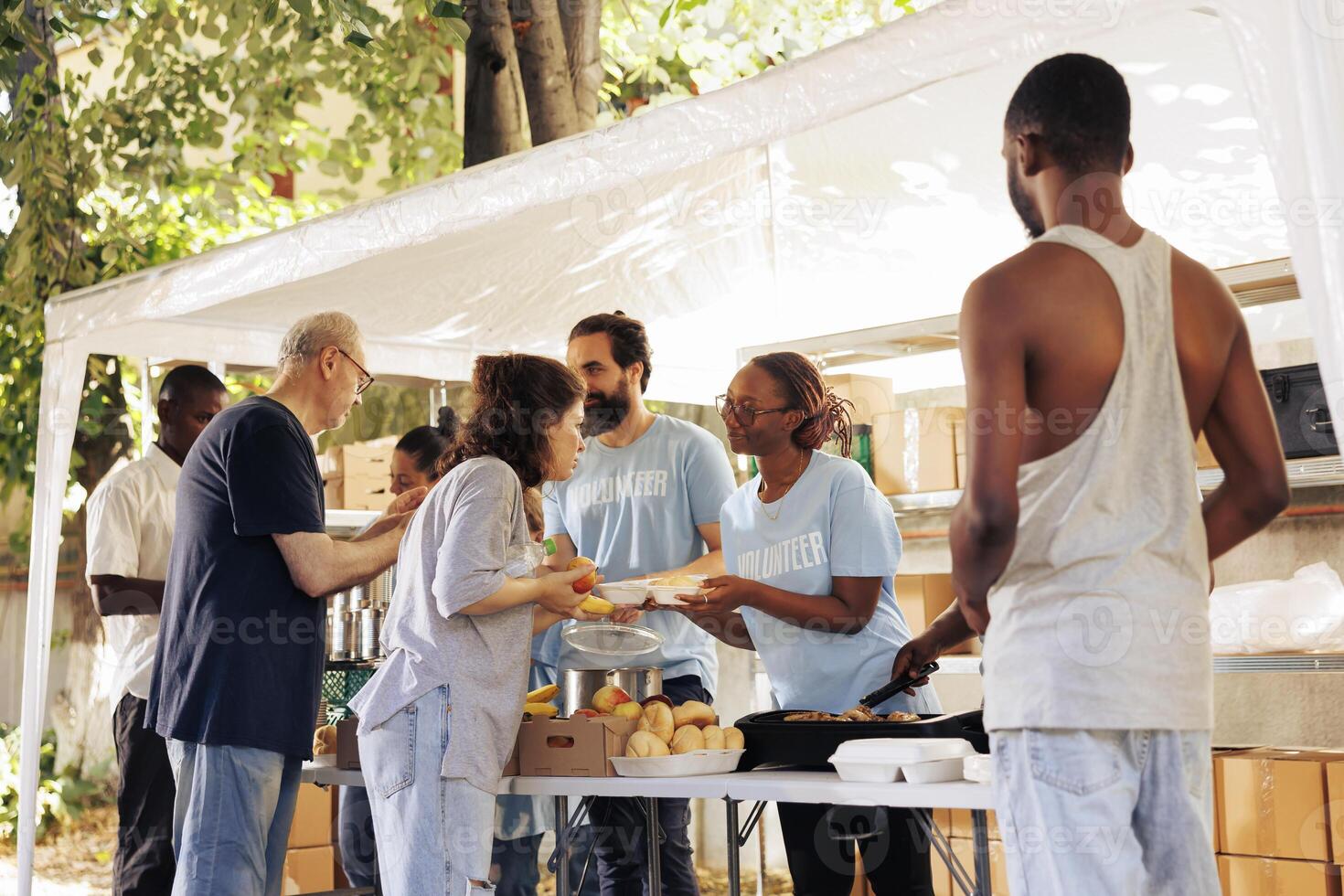 Humanitarian aid group assists in the distribution of contributions to people in need at a homeless and refugee shelter. Volunteers serve meals and provide help through a non-profit food bank. photo