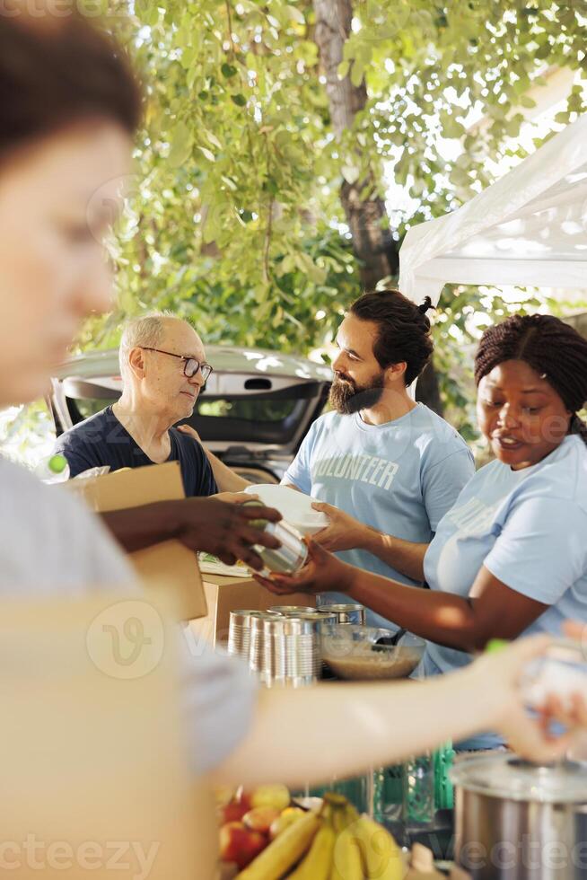 Multiracial humanitarian aid team combats hunger and poverty by providing donation boxes to the underprivileged. Friendly charity workers hand out packages to the poor needy and homeless people. photo