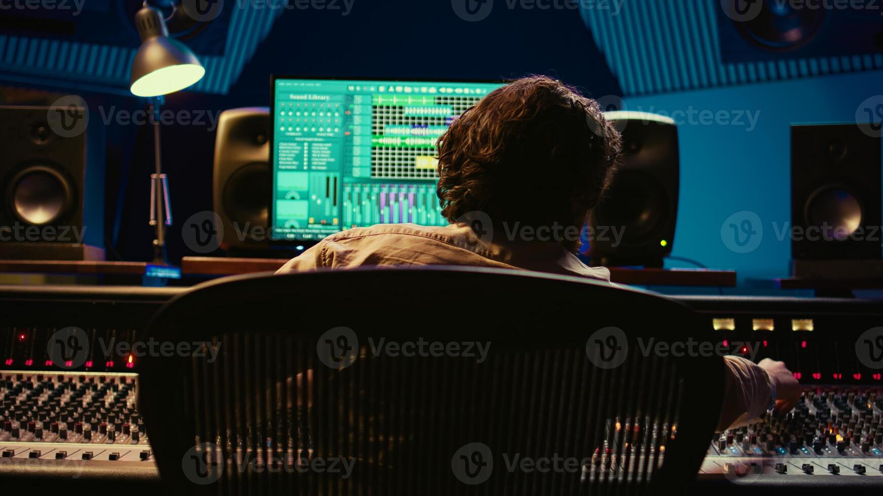 Audio expert does mixing and mastering on tracks using digital editing software in studio, producing new music. Skilled sound designer adjusting volume levels by using switchers and faders. Camera B. photo