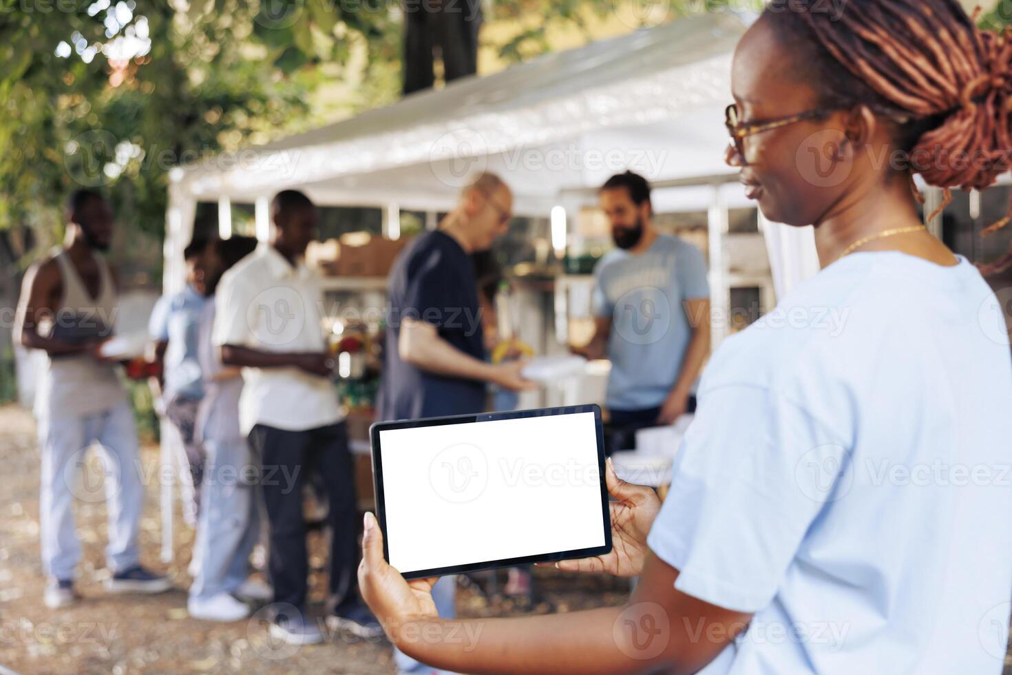 An isolated mockup template for philanthropic messages is held by young black woman holding a digital tablet. African american woman volunteer holding a smart device with a blank white screen display. photo