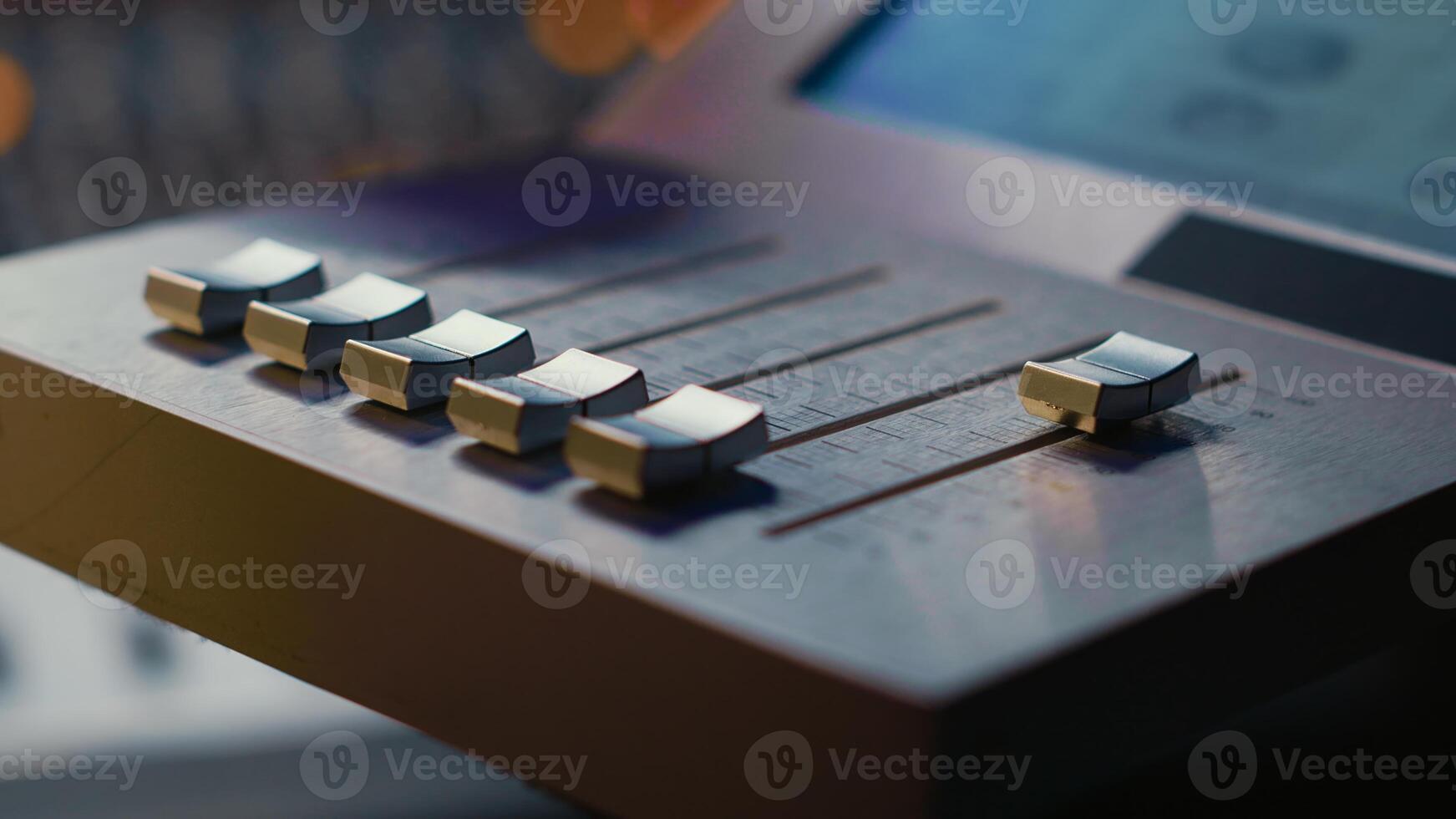 Sound engineer operating on motorized faders controller in professional studio, editing and mixing tracks to create a song. Audio technician works with sliders and soundboard panel. Camera A. photo