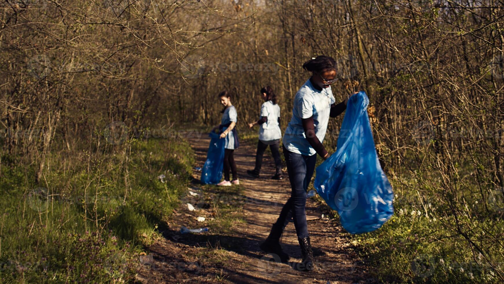 grupo de diverso activistas cosecha arriba el basura y el plastico desperdiciar, coleccionar y reciclaje basura en el bosque. personas haciendo voluntario trabajo a limpiar el natural hábitat. cámara b. foto