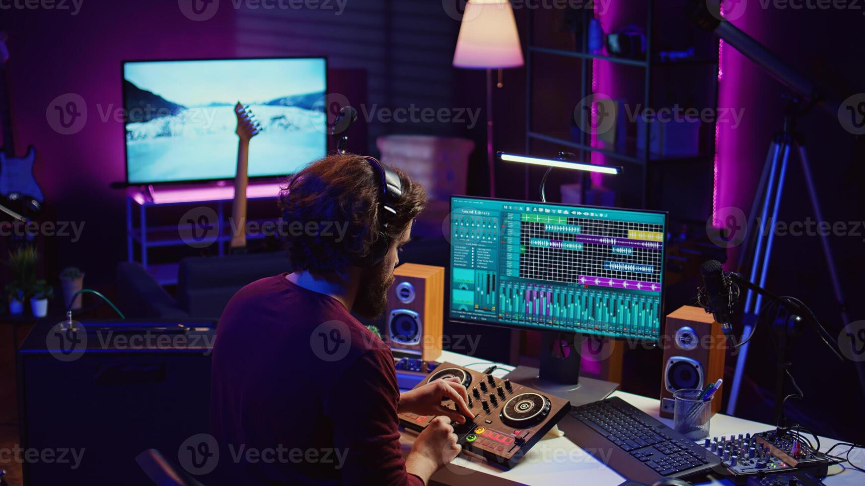 Sound engineer synchronizing and audio tracks in his home studio, editing techniques on recordings. Young artist adjusting music volume after mixing and mastering tunes with amplifier. Camera B. photo