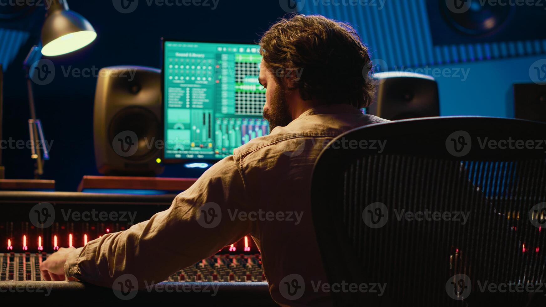 Sound designer mixing and mastering tracks on audio console in control room, using daw software on computer and editing files. Technician creating new music in professional studio. Camera A. photo