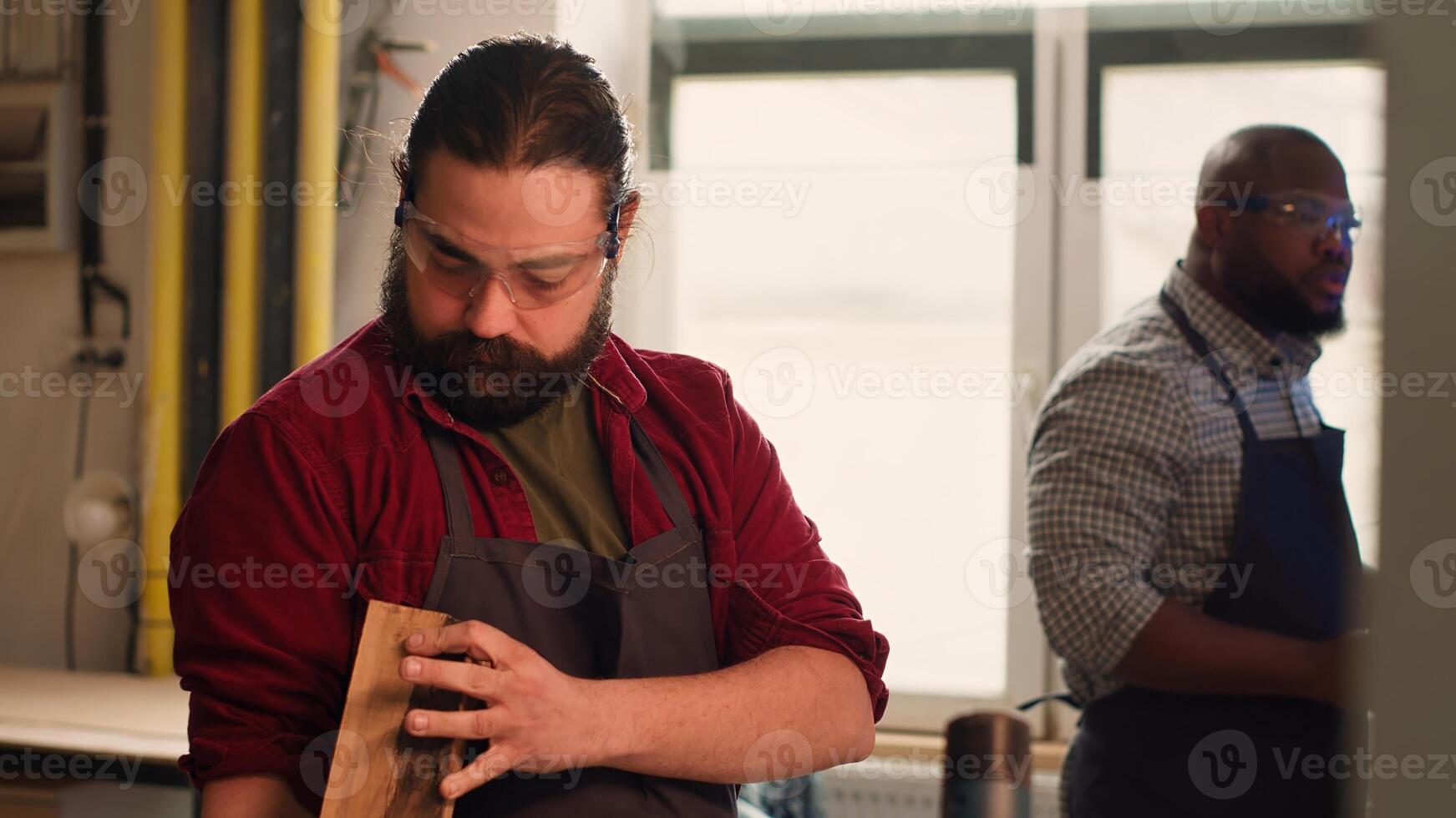 Manufacturer putting safety goggles on while selecting quality wood materials meeting client commission requirements. Woodworking expert doing quality assurance on timber block, camera A photo