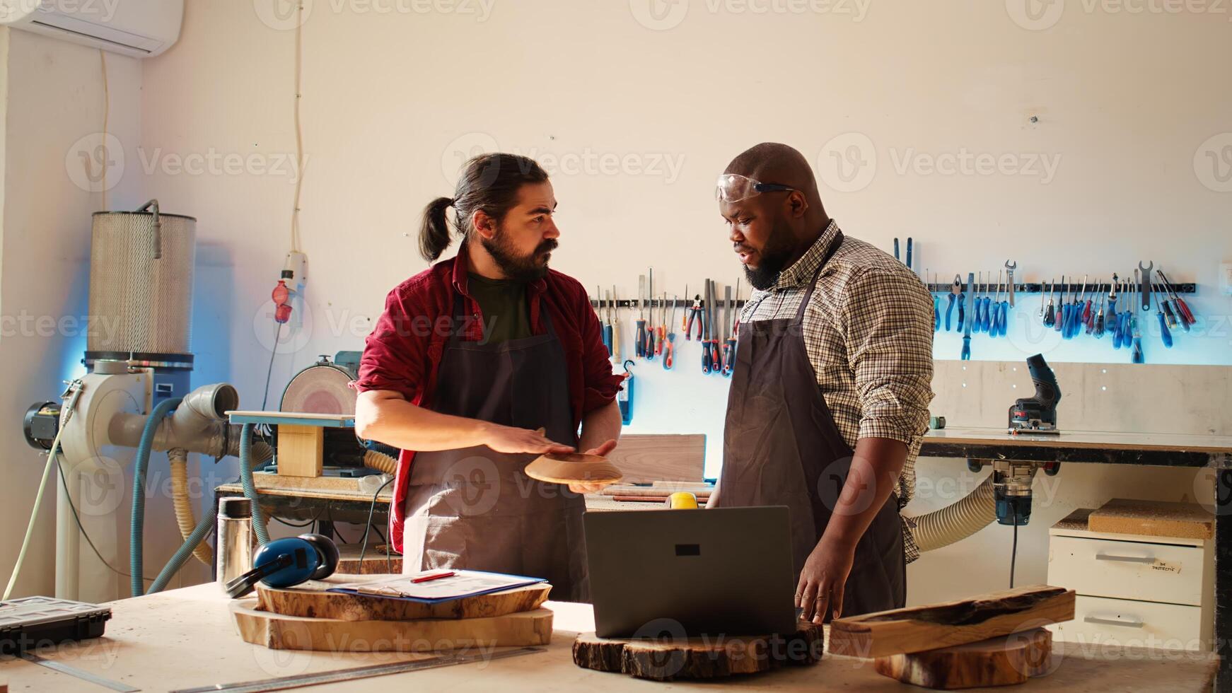 Carpenter and african american coworker verifying finished wood art product before sending it to client. Artisan and apprentice inspecting wooden object to correspond to requirements photo