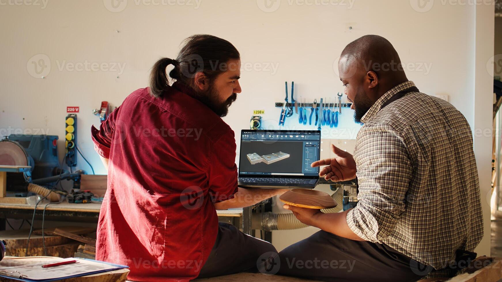 africano americano fabricante y colega comparando madera Arte pedazo con esquemático desplegado en canalla software en ordenador portátil. carpintería profesionales comprobación cruzada de madera objeto con Plano, cámara si foto