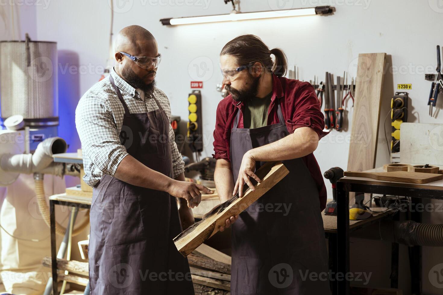 Carpenter holding timber block, brainstorming with coworker next steps in wood processing. Manufacturer in joinery and african american apprentice discussing what to do with piece of wood photo