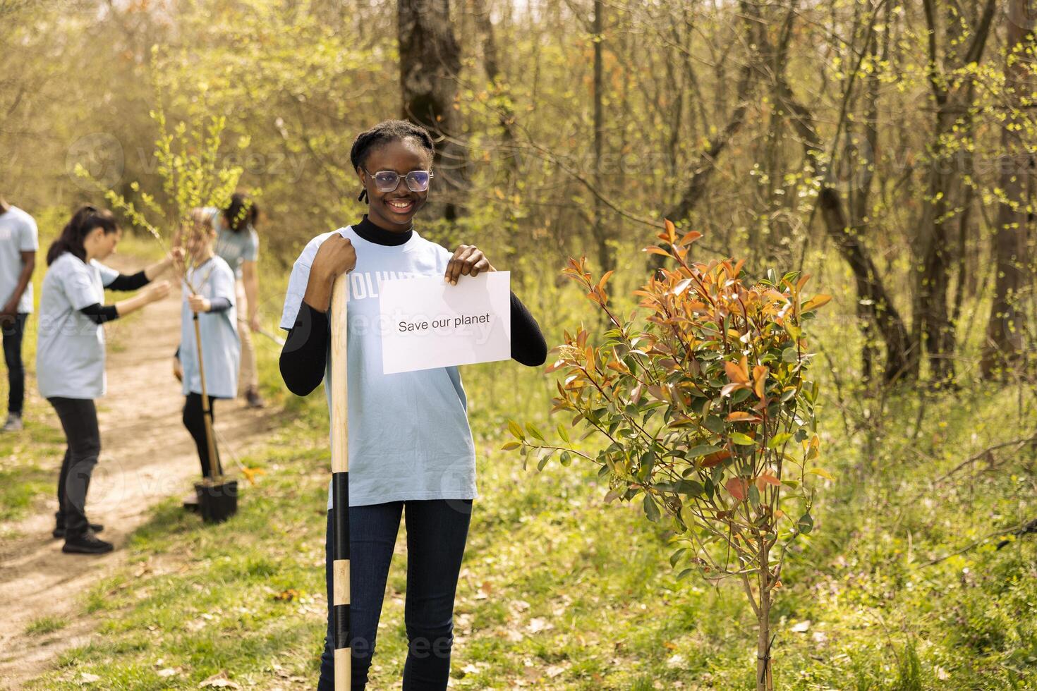 Portrait of african american girl holding banner with save our planet message, spreading ecological justice and awareness. Teenager activist posing with a poster to fight environmental pollution. photo