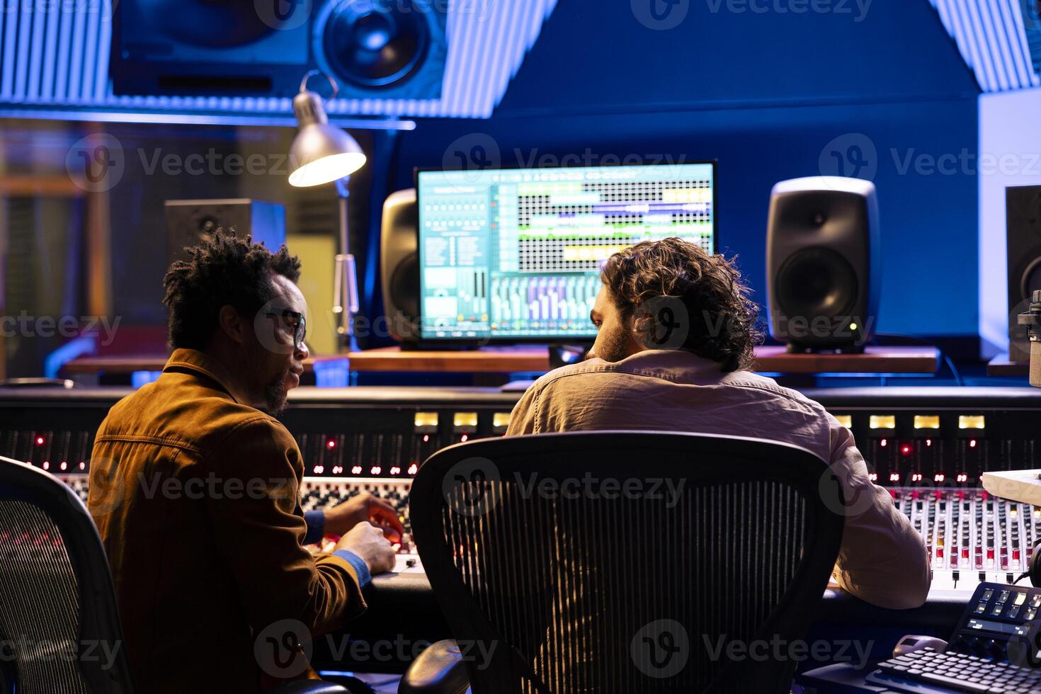 Team of sound technician and singer working on new music, mixing tunes on digital software in control room. Musician and producer collaborating on a new album, mixing and mastering tracks. photo