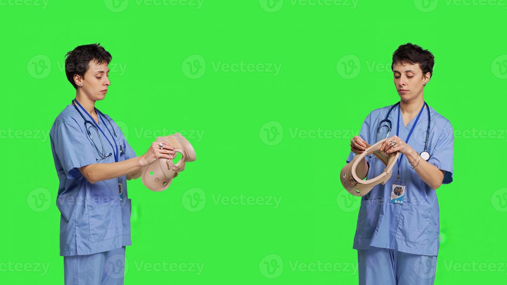 Specialist presenting cervical neck collar used for physical therapy and trauma after an accident or fracture, greenscreen backdrop. Nurse shows orthopedics brace to help with spine injury. Camera B. photo