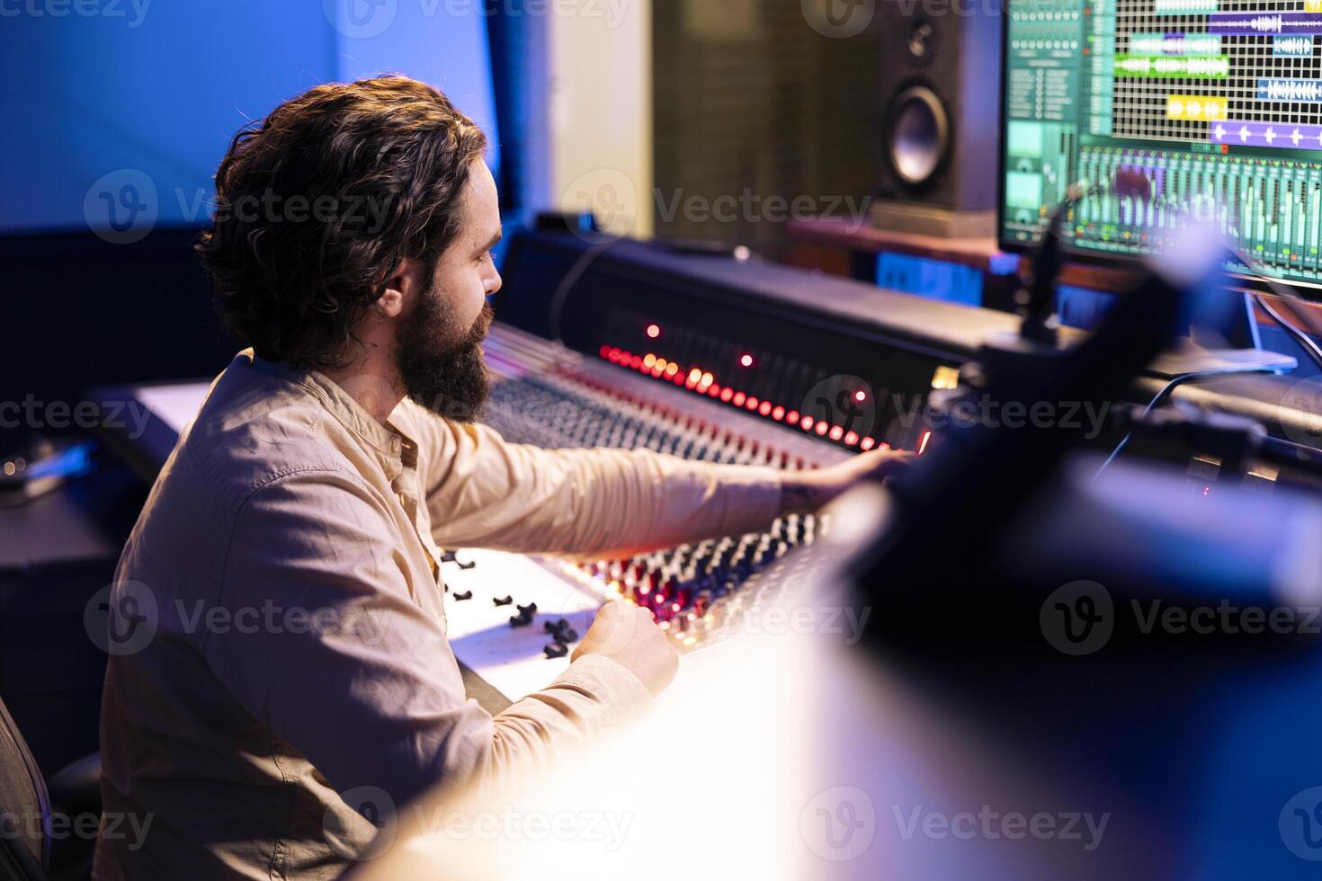 Music producer working on a new album in control room at studio, recording and processing sounds before editing in post production. Audio technician using daw software and mixing console. photo