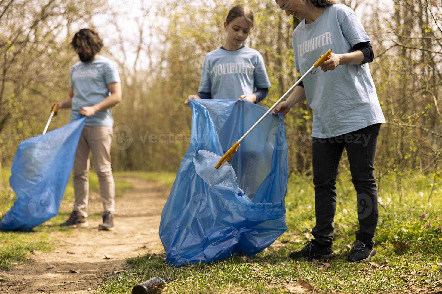 Diverse people collecting rubbish and storing in the trash disposal bag, picking up junk and plastic bottles to help with pollution. Clearing the forest, ecosystem protection. photo