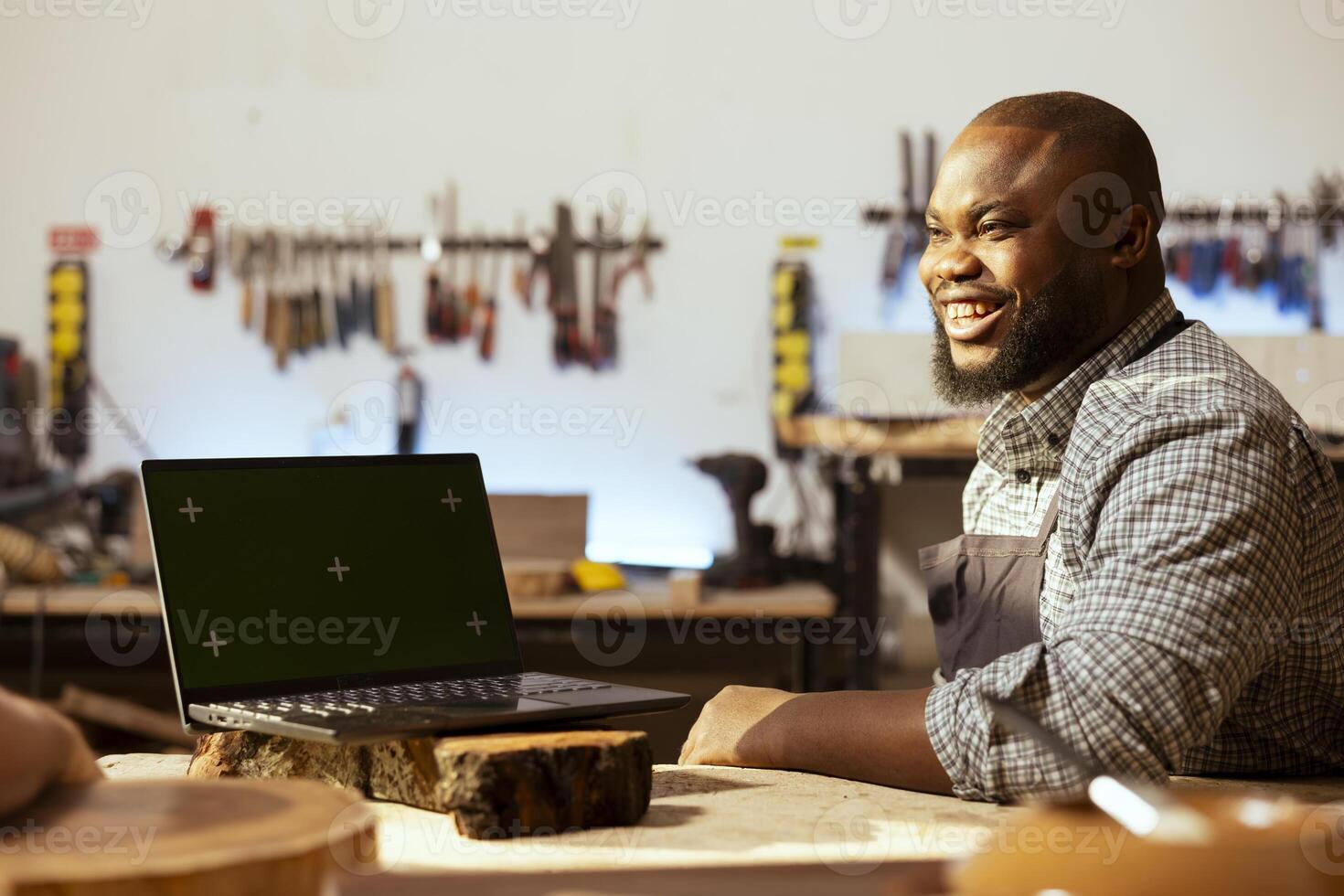 Joyful woodworker and BIPOC coworker using CAD software on green screen laptop to design wooden objects. Cheerful carpenters using program on mockup notebook to plan furniture assembling in joinery photo